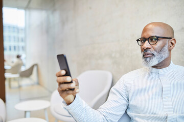 Portrait of bald mature businessman with cell phone