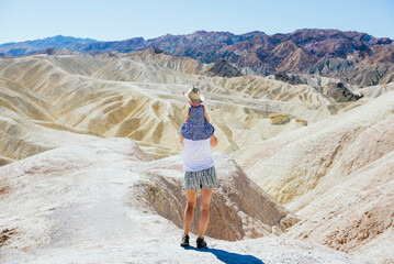 USA, California, Death Valley National Park, Twenty Mule Team Canyon, back view mother carrying...