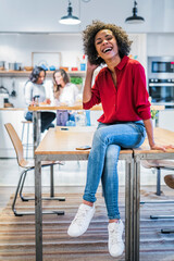 Portrait of laughing woman sitting on table