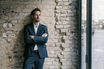Portrait of businessman leaning against brick wall