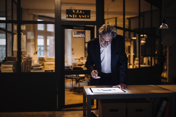 Senior businessman looking at shining tablet in office