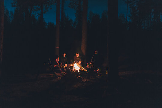 Friends sitting at campfire in the woods