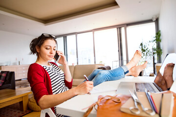 Woman on the phone working at desk at home