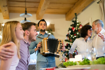 Young man playing accordion for family at Christmas