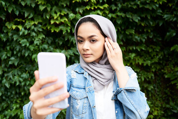Young woman looking at her phone screen wearing hijab