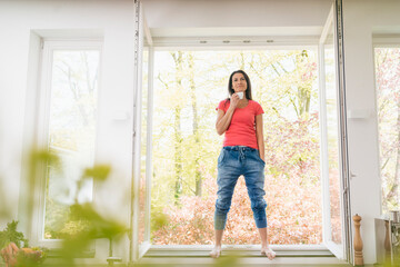 Smiling woman standing in kitchen on windowsill