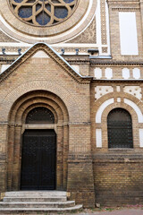 Side entrance door of the Synagogue of Novi Sad, surrounded by its elaborate facade and two colorful stained glass windows, Novi Sad, Serbia