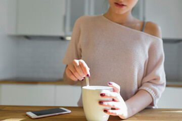 Female teenager with mug and smartphone in the kitchen