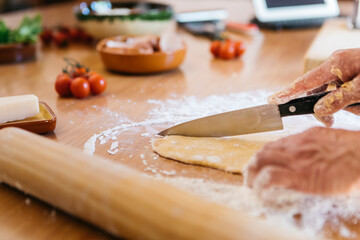 Hands cutting dough for fresh ravioli