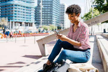 Businesswoman using smartphone, sitting on stairs