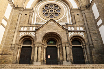Obraz premium The elaborate facade of the Synagogue of Novi Sad around its main entrance door, decorated with a colorful stained glass window and reliefs, stucco, columns and other details, Novi Sad, Serbia