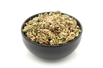 Close-up of Dry Organic Sanjivini Booti (Selaginella bryopteris), in black ceramic bowl. Isolated on a white background.
