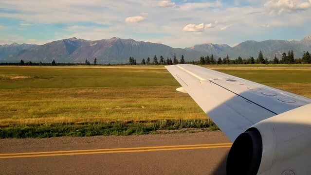 A Plane Taxis on the Runway at a Mountain Airport in the Kootenays - Sunny Summer View from Inside the Jet from a Window Seat