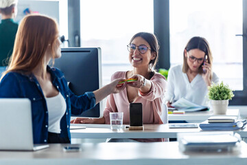 Businesswoman giving on notepad her colleague
