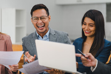 Diverse group of office colleagues laughing together during a meeting.
