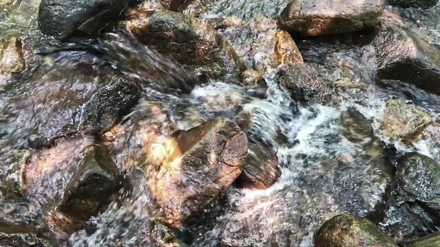 Gurgling river water over rocks, water flowing between large rocks in the river, clear water flowing in summer, flowing water background video in 4k