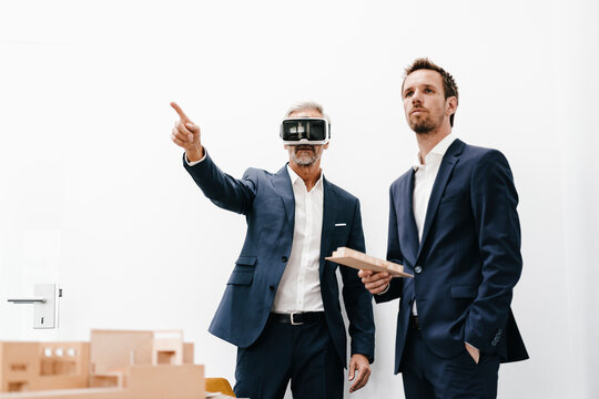 Two businessmen with VR glasses and architectural model