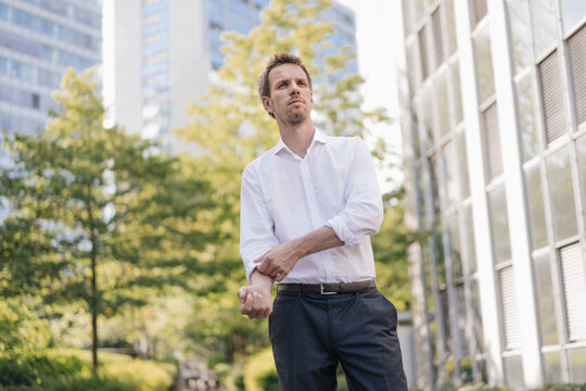 Portrait of confident businessman in the city rolling up his sleeves - Powered by Adobe