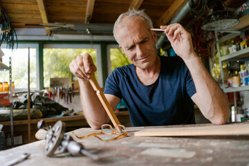 Mature man at workbench in his workshop thinking