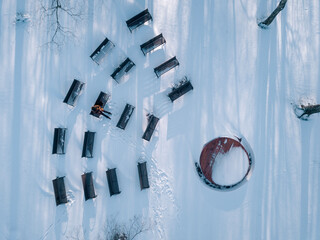 Man sitting on bench in snow-covered park, drone view