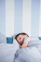 Little boy sleeping on bed in the morning