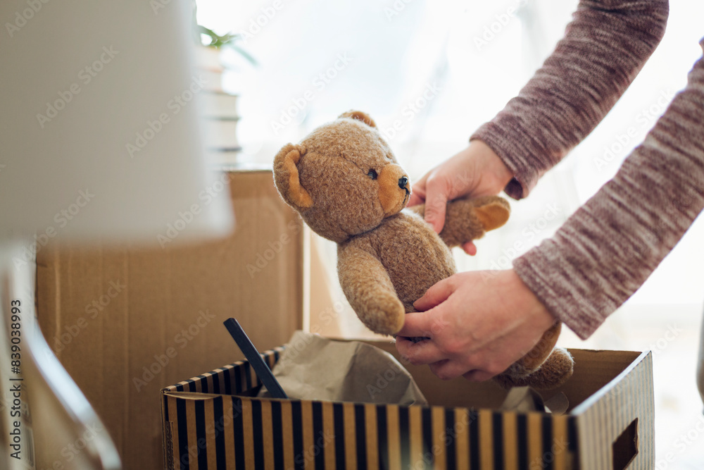 Wall mural close-up of woman unpacking cardboard box in new home taking out teddy bear