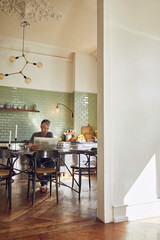 Mature man sitting in kitchen reading newspaper