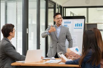 Group of Asian businessmen are presenting graphs on a whiteboard.
