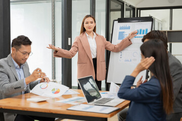 Group of Asian businessmen are presenting graphs on a whiteboard.