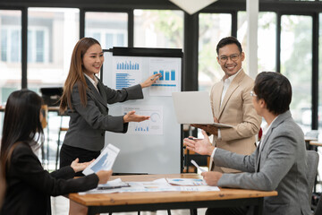 Group of Asian businessmen are presenting graphs on a whiteboard.