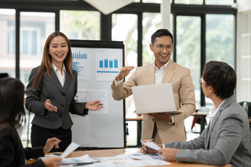 Group of Asian businessmen are presenting graphs on a whiteboard.