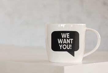 We want you message on a speech bubble printed on a coffee mug over the table.