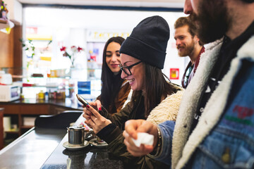 Smiling woman using smart phone while enjoying with friends in cafe