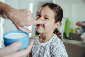 Father putting facial cream on daughter?s face