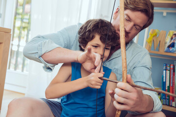 Father showing son how to use self-made bow and arrow