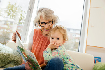 Pre-school teacher reading with child in kindergarten