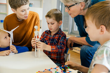 Children and pre-school teachers with wind turbine and anatomical model in kindergarten