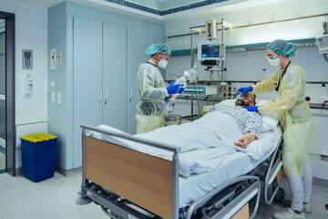 Doctors caring for patient in emergency care unit of a hospital changing breathing from oxygen mask to bag valve mask