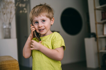 Portrait of smiling little boy on the phone at home