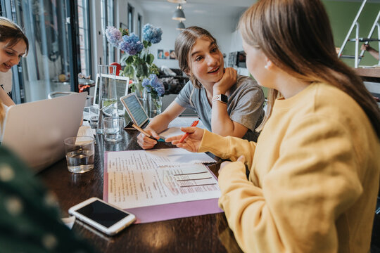 Teenage girls studying and learning from home, assisting eachother
