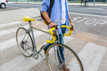 Young man pushing his bike on zebra crossing, partial view