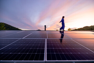 Rooftop with solar panels on house in mountains, woman walks alone enjoying sunset. Energy...