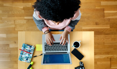 Top view of young woman working from home using laptop