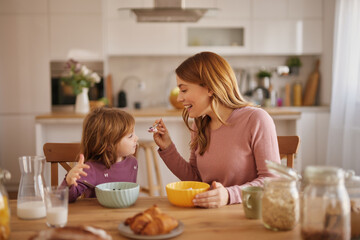 Mother having a breakfast with her little girl in the kitchen
