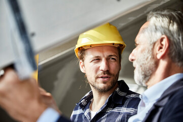Architect and worker talking at the window on a construction site
