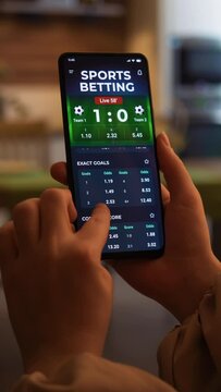 Making online bet on sports betting app. Watching live football score broadcast on a gambling smartphone application and gambling. Internet gambling concept. Fictional Interface, vertical video.