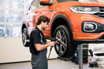 Car mechanic in a workshop changing tire