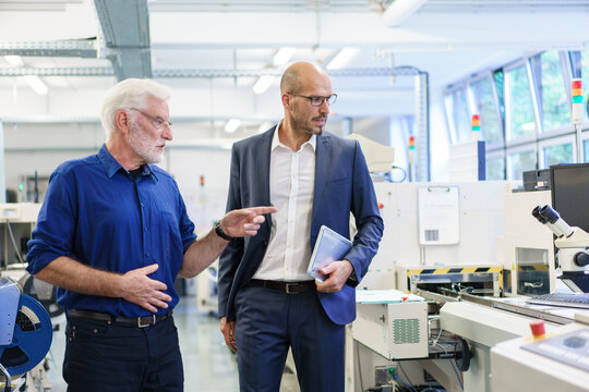 Senior male manager pointing while discussing with colleague at laboratory