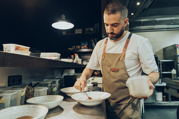 Chef arranging food on plate before serving in restaurant