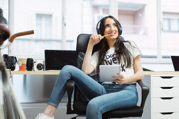 Casual young woman with notepad and headphones in coworking space